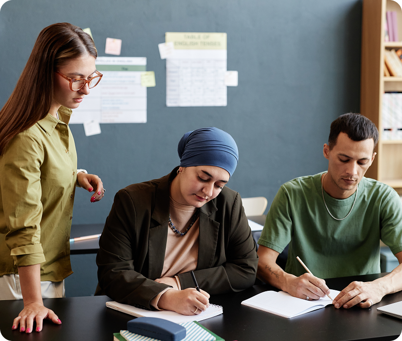 Students writing at a table with a tutor